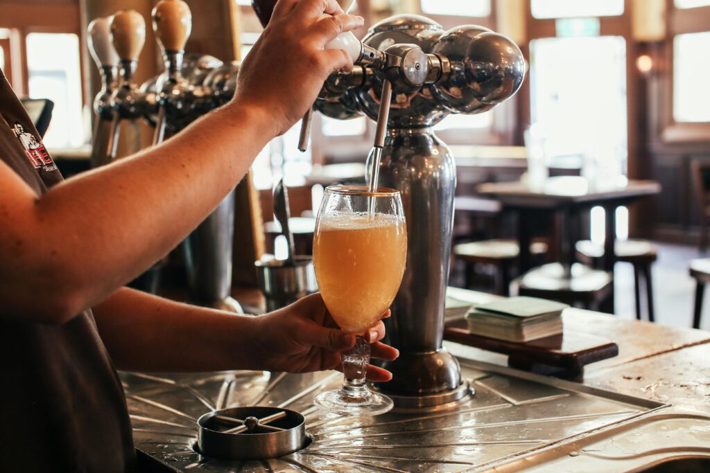 Bartender skillfully pouring a fresh draft beer at a lively bar counter.